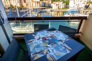 a table on a balcony with a view of a marina at MER.Veilleuse YourHostHelper in Gruissan