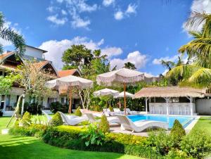 un complejo con piscina, sillas y sombrillas en 37 Sunset Village Bali, en Canggu