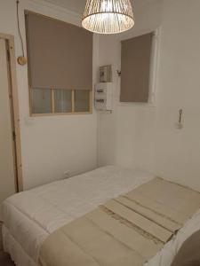 ein weißes Zimmer mit einem Bett und einem Kronleuchter in der Unterkunft Mimi&Cosy, appartement en bord de mer à Six-Fours-les-plages in Six-Fours-les-Plages
