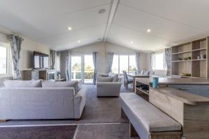 a living room with couches and a kitchen with windows at Stunning 6 Berth Lodge With Partial Sea Views In Suffolk Ref 68007cr in Lowestoft