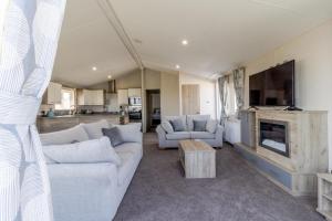 un soggiorno con 2 divani bianchi e una TV di Stunning 6 Berth Lodge With Partial Sea Views In Suffolk Ref 68007cr a Lowestoft