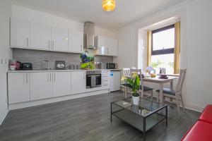 a kitchen with white cabinets and a table in a room at Station Signature Apartment near Lanark in Carstairs