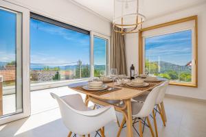 a dining room with a table and chairs and large windows at Villa Noha in Bribir