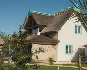 una casa con tetto di paglia sopra di Laguna Vadu a Vadu