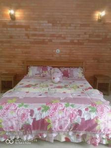 Una cama con una manta rosa con un animal de peluche. en Warung Rizka en Probolinggo