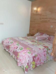 Una cama con una colcha rosa con rosas. en Warung Rizka en Probolinggo