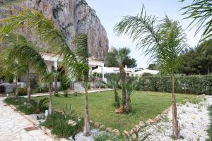 een tuin met palmbomen voor een huis bij Casa Enza di fronte la Tonnara in San Vito lo Capo