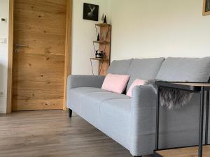 a living room with a gray couch with pink pillows at Ferienbungalow Kampenheissji in Wiltingen