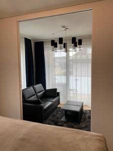 a living room with a black couch and a chair at See & You Ferienwohnung mit Hotelanbindung in Pörtschach am Wörthersee