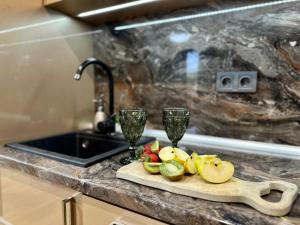 a cutting board with fruit and wine glasses on a kitchen counter at Vitosha Terrace 1BR Apartment with Parking in Sofia