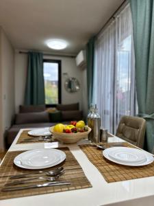 una mesa con platos y un bol de fruta en ella en Vitosha Terrace 1BR Apartment with Parking, en Sofía