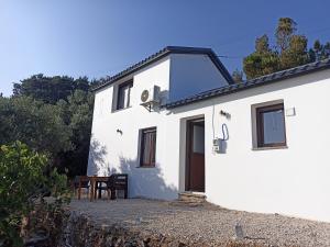 a white house with a table and chairs at Aloni Cottage above Aegean Sea in Raches