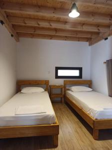 two twin beds in a room with wooden ceilings at Aloni Cottage above Aegean Sea in Raches