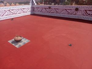 an empty courtyard with a pot on a red floor at Dar Ilyana in Tamezmoute