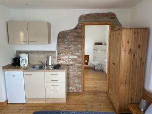 a kitchen with white cabinets and a brick wall at Pension Landhaus an der Saale in Bernburg