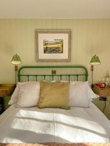 a bed with a green head board and two lamps at The Crown Inn in Lanlivery