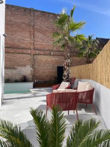 patio z 2 czerwonymi krzesłami i palmą w obiekcie Casa Palma Pals 2 w mieście Pals