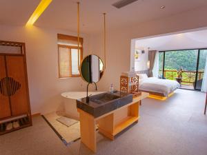 a bathroom with a sink and a bed and a mirror at Mount View Cottage in Zhangjiajie