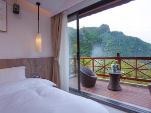 a bedroom with a bed and a balcony with a view at Mount View Cottage in Zhangjiajie