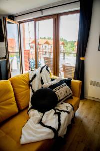 a yellow couch with blankets on it in a living room at Apartament Może Morze Łebska Ostoja in Żarnowska