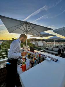 a man making a drink at a bar on a rooftop at Hotel Indigo Cagnes-sur-Mer by IHG in Cagnes-sur-Mer