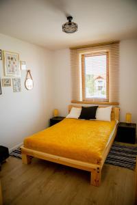 a bedroom with a large yellow bed with a window at Apartament Może Morze Łebska Ostoja in Żarnowska