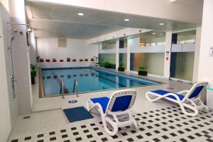 a pool with two chairs and a swimming pool at Best Western Premier Muscat in Muscat