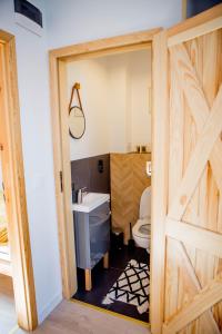 a bathroom with a wooden door and a toilet at Apartament Może Morze Łebska Ostoja in Żarnowska