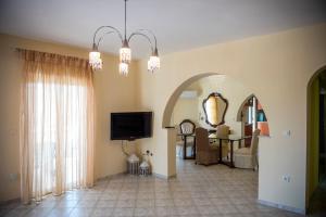 a living room with a chandelier and a room with a tv at Villa Maria in Armenoí