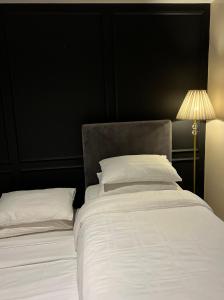 a bed with white sheets and pillows next to a lamp at 2-Bedroom Manhattan, Cubao Condo in Manila