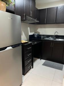 cocina con armarios negros y suelo blanco en 2-Bedroom Manhattan, Cubao Condo, en Manila