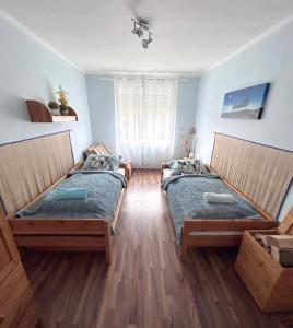 two beds in a room with blue walls and wooden floors at Diókert Vendégház in Komjáti