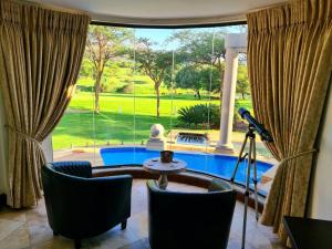 una sala de estar con vistas a la piscina a través de una ventana en The Villa Luxe Hartbeespoort Spacious Golf & Wildlife Estate en Hartbeespoort