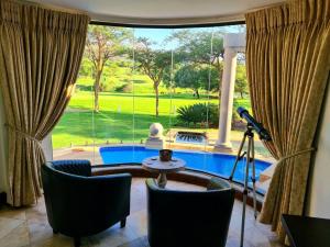 a living room with a view of a pool through a window at The Villa Luxe Hartbeespoort Spacious Golf & Wildlife Estate in Hartbeespoort