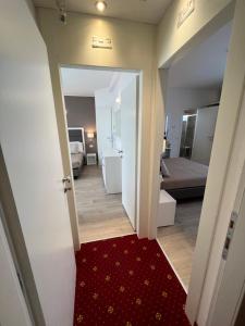un corridoio che conduce a una camera da letto con tappeto rosso di Hotel Ardea a Riccione