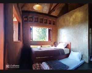 een kleine kamer met twee bedden en een raam bij Baandindon Private Earthhouse Homestay in Mae Rim