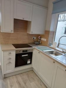 a kitchen with white cabinets and a sink and a stove at Private rooms with breakfast in Bishop Auckland in Bishop Auckland