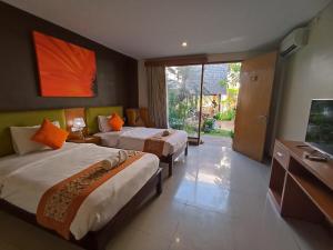 a hotel room with two beds and a television at Abian Harmony Hotel in Sanur