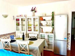 a kitchen with a table with chairs and a refrigerator at CasAzul in Olhão