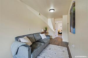 a living room with a gray couch and a hallway at Skeetawk Ski Lifts - Hatcher Pass Mountain Home Rental Palmer Alaska in Palmer