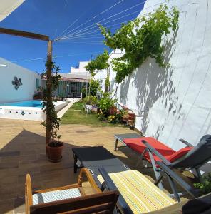 un patio con sillas, mesas y una sombrilla en Casa con piscina cerca de Sevilla, en Carrión de los Céspedes