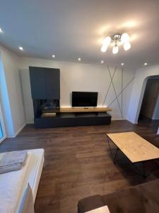 a living room with a flat screen tv and a table at LUNA Apartamentai in Akmenė