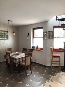 a dining room with a table and chairs and two windows at chata ORAVSKA priehrada in Námestovo