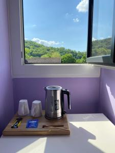 - une cafetière sur un plateau en bois devant une fenêtre dans l'établissement Moulin de Latouille, à Latouille-Lentillac