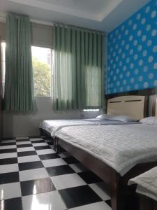 a bedroom with two beds and a checkered floor at KHÁCH SẠN SAO MAI in Ho Chi Minh City