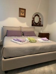 un letto con asciugamani viola e verdi di Al Vecchio Platano guest house a Pitigliano