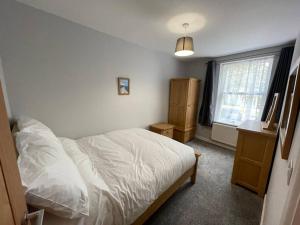 a bedroom with a white bed and a window at Hot Tub, Newly refurbished 4 bed, Dog friendly. in Torquay