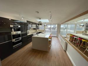 a large kitchen with black and white appliances and wooden floors at Hot Tub, Newly refurbished 4 bed, Dog friendly. in Torquay