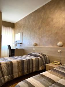 a hotel room with two beds and a desk at Hotel Vallisdea in Sala Consilina