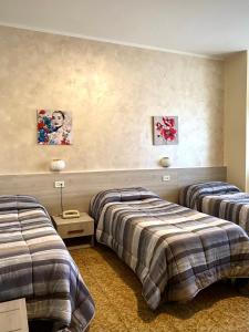 Habitación con 2 camas y 2 cuadros en la pared. en Hotel Vallisdea en Sala Consilina